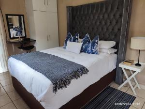 1 dormitorio con 1 cama grande con almohadas azules y blancas en Onyx Luxury cottage, en Randburg