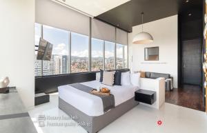 1 dormitorio con cama blanca y ventanas grandes en Kukun Collection, en Ciudad de México