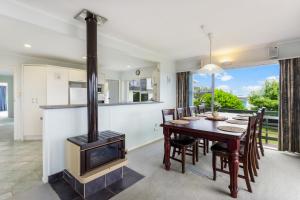 a kitchen and dining room with a wood stove at Harbour Retreat with sea views and BBQ in Whangaparaoa