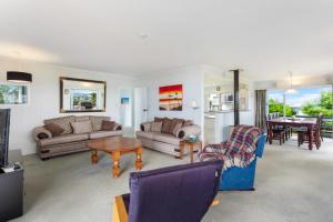 a living room with couches and a table at Harbour Retreat with sea views and BBQ in Whangaparaoa