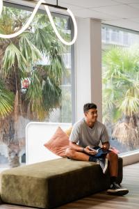 un hombre sentado en un sofá frente a una ventana en Haka House Auckland City, en Auckland