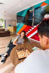 una mujer sentada en una mesa jugando ajedrez en Haka House Auckland City, en Auckland