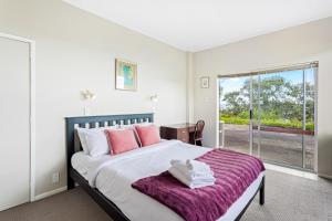 a bedroom with a large bed with a purple blanket at Harbour Retreat with sea views and BBQ in Whangaparaoa
