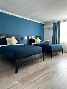 a bedroom with two beds and a blue wall at Hometel Suites in Los Angeles