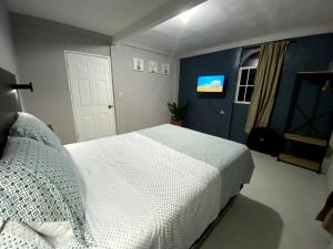 a bedroom with a white bed and a blue wall at Habitación cerca del aeropuerto #1 