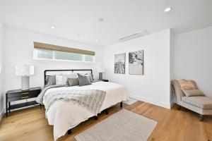een witte slaapkamer met een bed en een stoel bij 4 Bedrooms in BRAND NEW Luxury built Home walk to the beach in Newport Beach