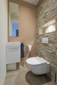 baño con aseo blanco y pared de piedra en Lovely Apartment With Workspace Jack Nr 5, en Roosendaal