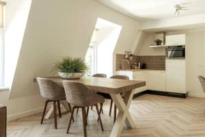 cocina y comedor con mesa de madera y sillas en Lovely Apartment With Workspace Jack Nr 5, en Roosendaal