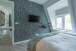 - une chambre avec un lit et une télévision murale dans l'établissement Lovely Apartment With Workspace Jack Nr 5, à Roosendaal