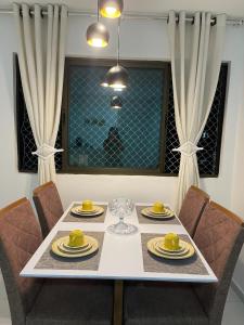mesa de comedor con sillas y mesa blanca con platos amarillos en Apartamento Moderno e Tranquilo, en Recife