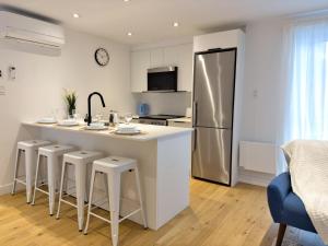 een keuken met een groot eiland met krukken en een koelkast bij Superb 2 BedR Haven 2mins from Frontenac Metro! in Montreal