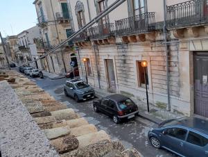 due auto parcheggiate in una strada cittadina con edifici di Casa Nicotera a Noto