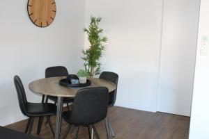 einen Esstisch mit Stühlen und eine Uhr an der Wand in der Unterkunft CBD Elizabeth St Modern Townhouse - Secure Parking in Launceston