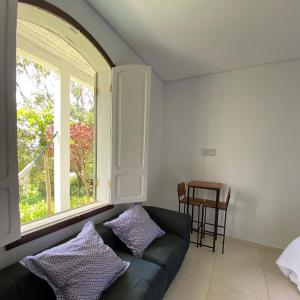 a living room with a couch and a window at Quinta Vogrande no bairro de Águas Santas entre Tiradentes e São João Del Rey in Tiradentes