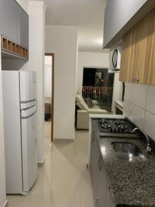 a kitchen with a white refrigerator and a sink at Apartamento Primavera in Boituva