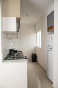 a white kitchen with a stove and a refrigerator at Apartamento Primavera in Boituva