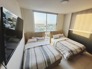 - 2 lits dans une chambre avec une grande fenêtre dans l'établissement Panama's Paradise Playa Blanca Ocean & Pool View, à Río Hato