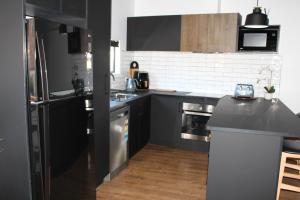 eine Küche mit schwarzen Schränken und einem schwarzen Kühlschrank in der Unterkunft CBD Elizabeth St Modern Townhouse - Secure Parking in Launceston