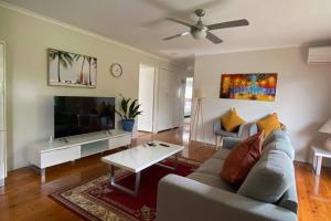 a living room with a couch and a tv at Spacious 4-Bedroom house in a shared property in Harristown