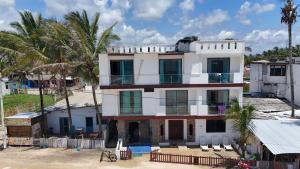 una casa blanca con palmeras delante en Hotel Sierra Negra en Puerto Villamil