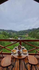 una mesa con platos de comida en el balcón en Lune chalé, en Santo Antônio do Pinhal