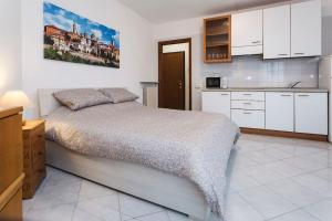 a bedroom with a bed and a kitchen with white cabinets at Loft alto con vista su Città Alta in Bergamo