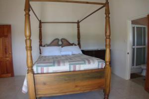 un letto in legno con struttura in legno in una stanza di Paradise Getaway a Calivigny
