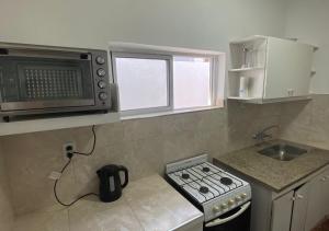 a small kitchen with a stove and a microwave at Casa con cochera in Villa Krause