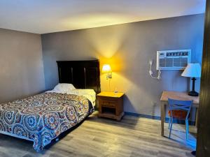een slaapkamer met een bed, een bureau en een tafel bij Clintonville Motel in Clintonville