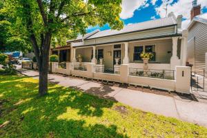 una casa con una recinzione bianca e un albero di Newly Renovated Victorian Townhouse In Bendigo CBD a Bendigo