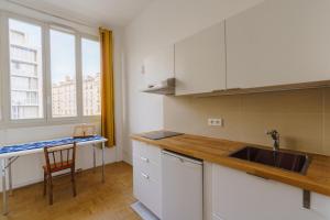 a kitchen with white cabinets and a sink and a window at Centrally-located Studio Reuilly-Diderot in Paris