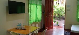 uma sala de jantar com uma mesa e uma televisão e cortinas verdes em Camguin Lanzones Resort em Balbagon