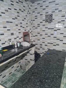 a bathroom with a sink and a tiled wall at Casa mobiliada para hospedagens e com piscina para o lazer in Bayeux