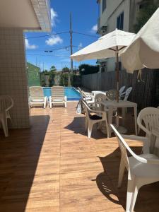 a patio with white chairs and tables and an umbrella at Apartamento centro de Paulista-Pe in Paulista