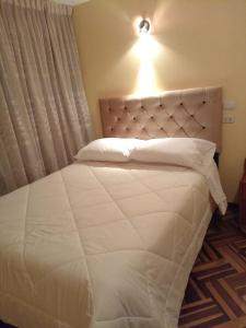 um quarto com uma cama branca e uma luz por cima. em HOSTAL SUIT ANDINA em Puno