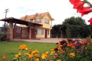une maison jaune avec des fleurs devant elle dans l'établissement Portal de las Flores, Alojamiento Rural, à Chía
