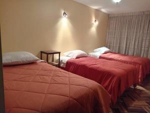 two beds in a hotel room with red sheets at HOSTAL SUIT ANDINA in Puno