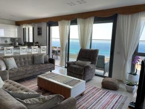 a living room with a couch and chairs and the ocean at Exquisite Sunset Penthouse in Haifa