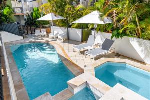 a swimming pool with two chairs and an umbrella at Eco Beach Resort in Byron Bay