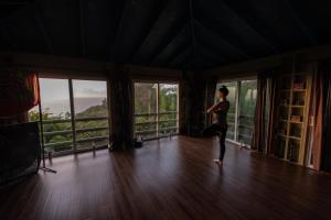a woman doing a pose in a room with windows at Maui Eco Retreat in Huelo