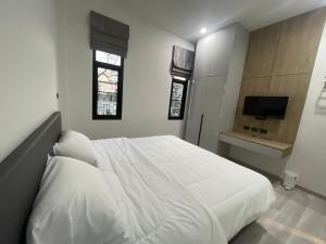 1 dormitorio con 1 cama blanca y TV en SS Home, en Ban Don Wai