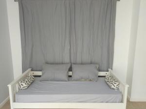 Cama blanca con sábanas y almohadas grises en Gasparetto Lofts en Godoy Cruz