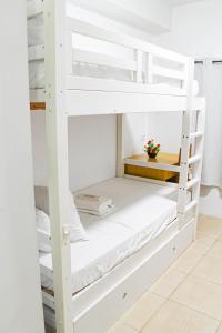 a bunk bed room with white bunk beds at Titan Condo at Studio City Tower 3 Alabang in Manila
