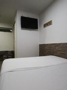 1 dormitorio con 1 cama blanca y TV de pantalla plana en HOTEL CASA GIRARDOT en Medellín