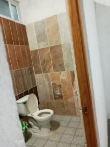 a bathroom with a toilet and a tiled wall at Casa de Descanso en Monterrico in Monterrico