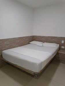 un letto bianco in una stanza con un muro di mattoni di HOTEL CASA GIRARDOT a Medellín