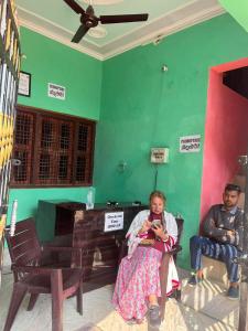 a man and a woman sitting in a room with a green wall at Indiana home stay in Khajurāho