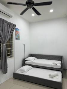 2 Betten in einem Zimmer mit Deckenventilator in der Unterkunft Roxy homestay in Alor Setar