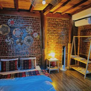 1 dormitorio con pared de ladrillo y cama con almohadas en Homestay Cánh Đồng - Lều Camping & Coffee, en Mộc Châu