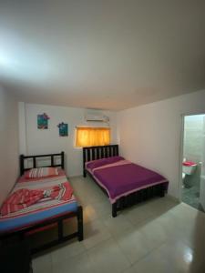 1 dormitorio con 2 camas y baño con ventana en HERMOSA CASA CAMPESTRE EN SANTA MARTA en Santa Marta